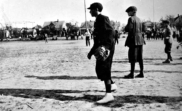 Photo of boys playing baseball on a school playground, ca. 1910.